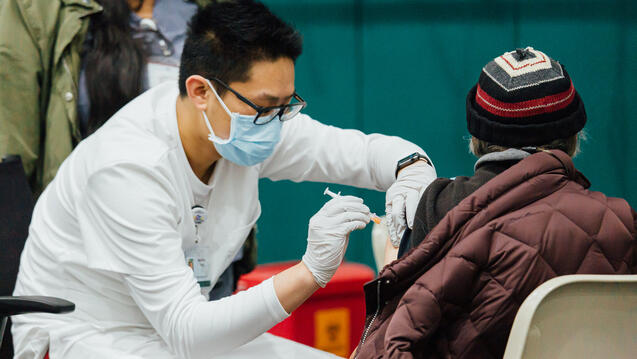 Norman Feng gives vaccination to patient.