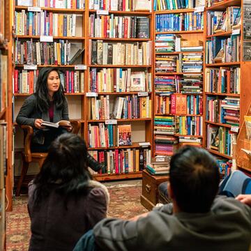 person reads reads a book to audience in a bookstore