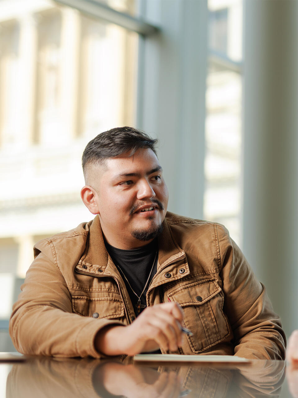 Graduate student wearing brown jacket chatting