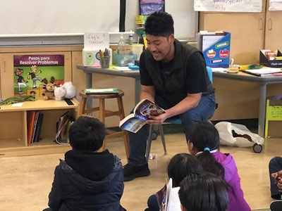 Christian Flores MA ’15 reading aloud to students in his classroom