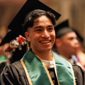 Graduate smiles during commencement ceremony.