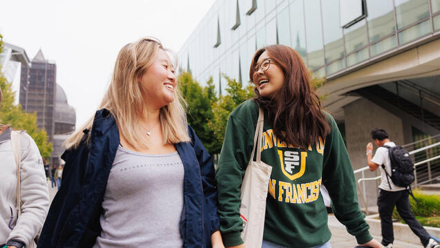 Two USF students walking and laughing on campus