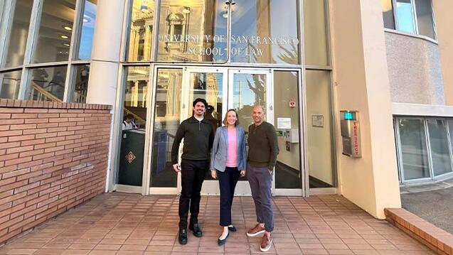 Three people standing in front of the School of Law