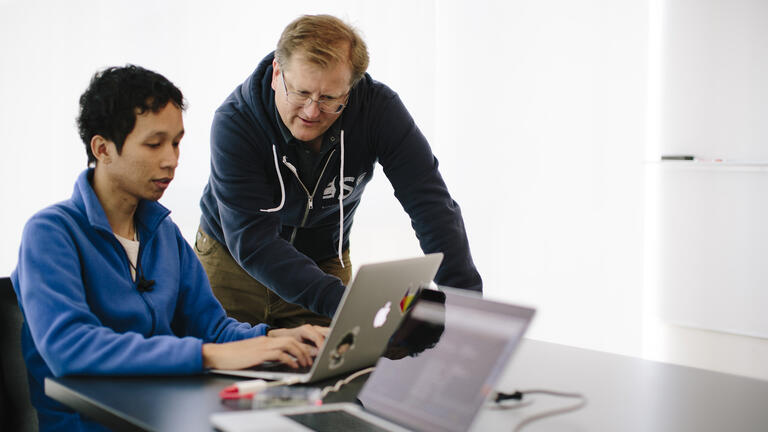 Student and instructor working on laptop.