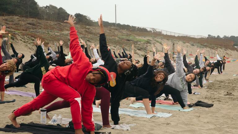 People doing yoga on the beach