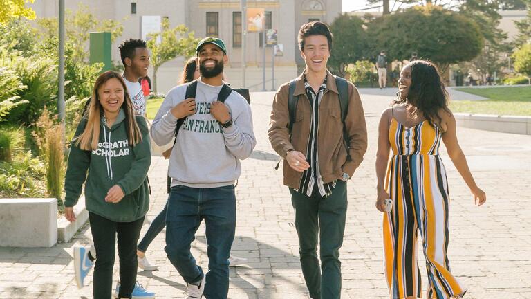 Group of students walk across Gleeson Plaza while talking.