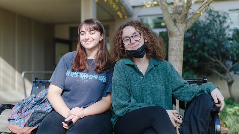 Two students sit on a bench.