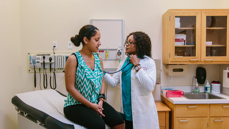 nursing student in scrubs holds stethoscope