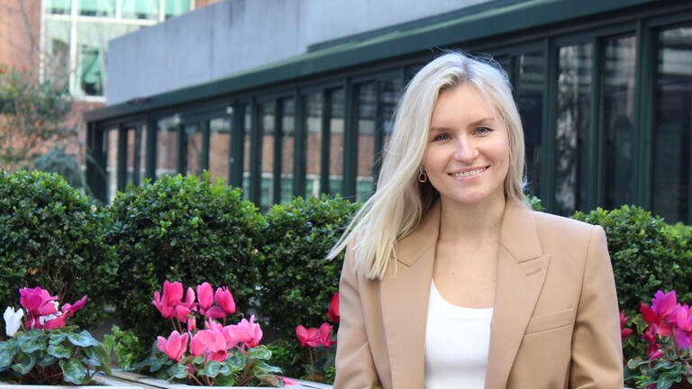 Karina poses in front of a row of flowers