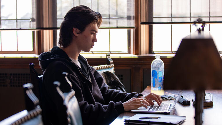 Student studies at a table in the Lone Mountain reading room.