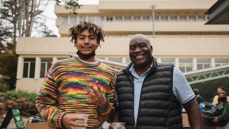 Student and parent pose in front of building