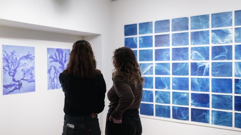 Two people standing in front of the Elemental Exposures exhibit