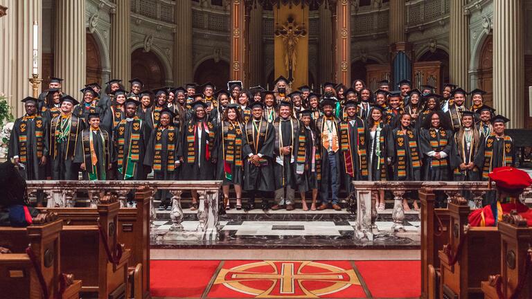 Graduates of BASE in full regalia gather in St Ignatius Church.