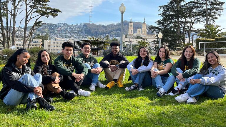 A group of students sit on the lawn on Lone Mountain.