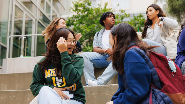 students sit together on campus steps