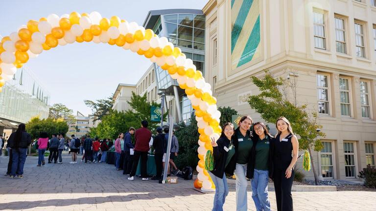 students on campus standing in front of a balloon arch