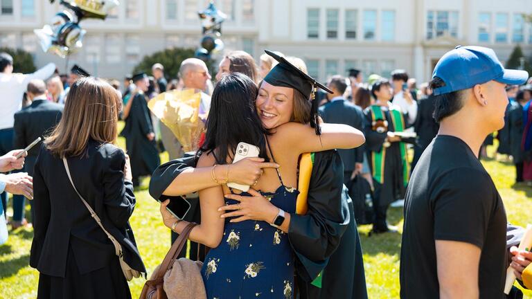 student graduate hugging guest on usf campus during commencement