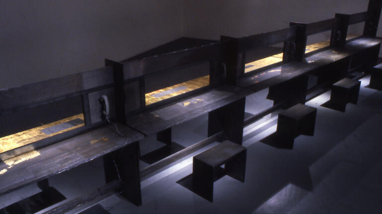 A row of dark wooden booths with stools and old-fashioned telephones arranged in front of them