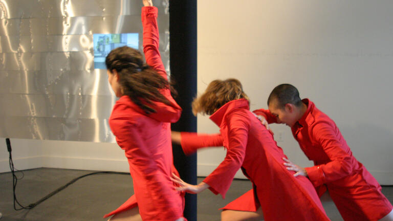 Three performers in red dresses in motion