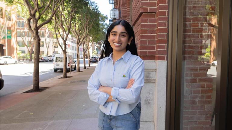 Student posing in front of a brick building