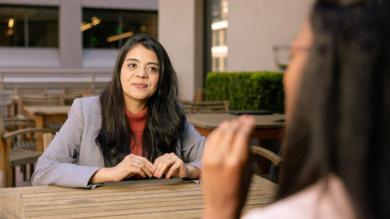 student in business attire sits outside