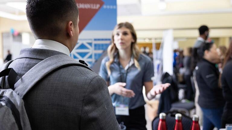 Rep at the Grad Fair talking to a student.