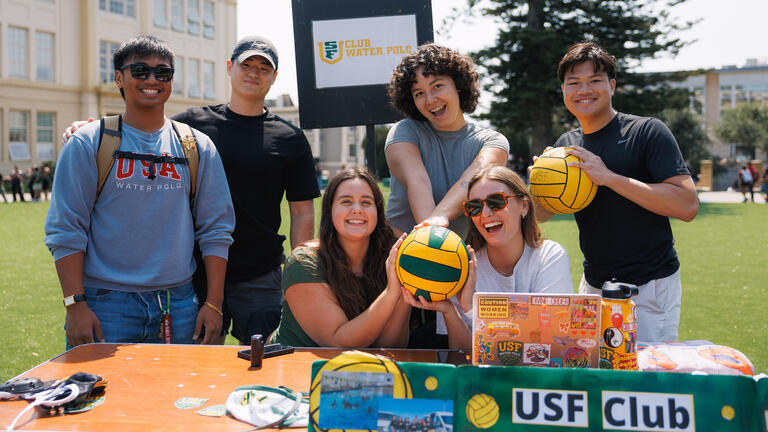 students hold water polo balls behind table during weeks of welcome