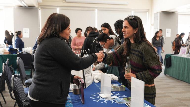 Student involved in the fair and shaking hands with the person tabling