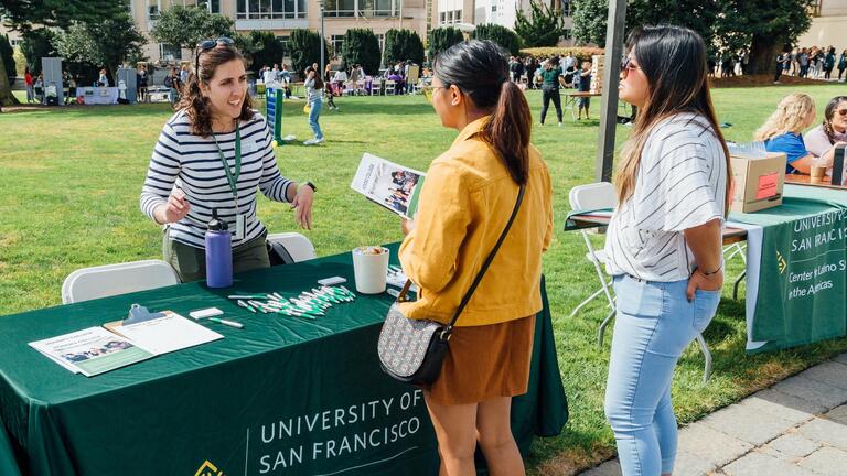 Students speaking with USF representative at a fair