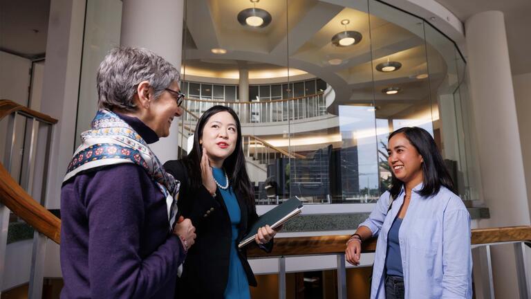 three women chatting in the law building atrium 