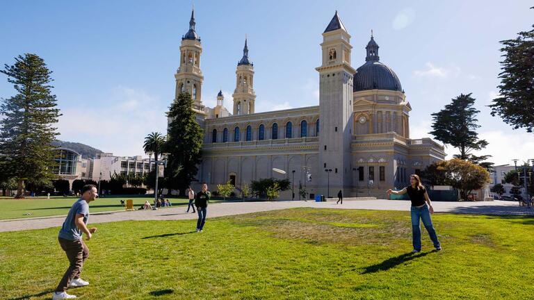 two people playing catch in front of st. ignatius