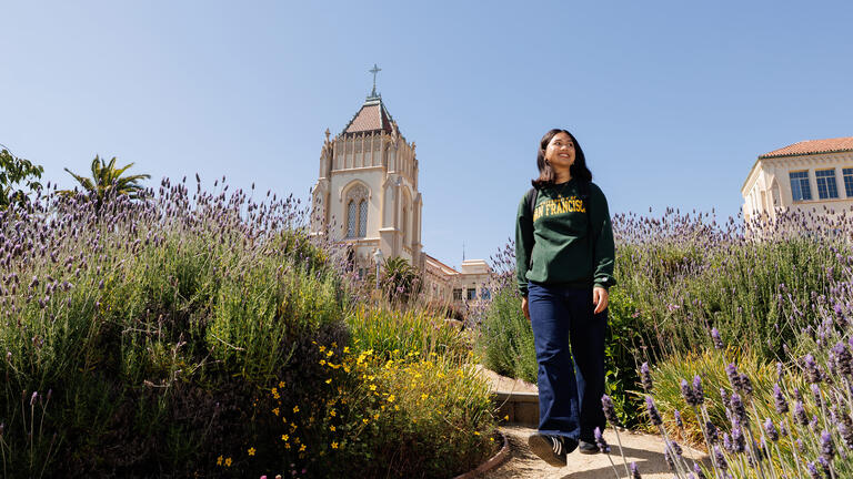 student walks along floral pathway on usf campus