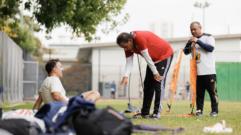 Three soccer players on the sideline.