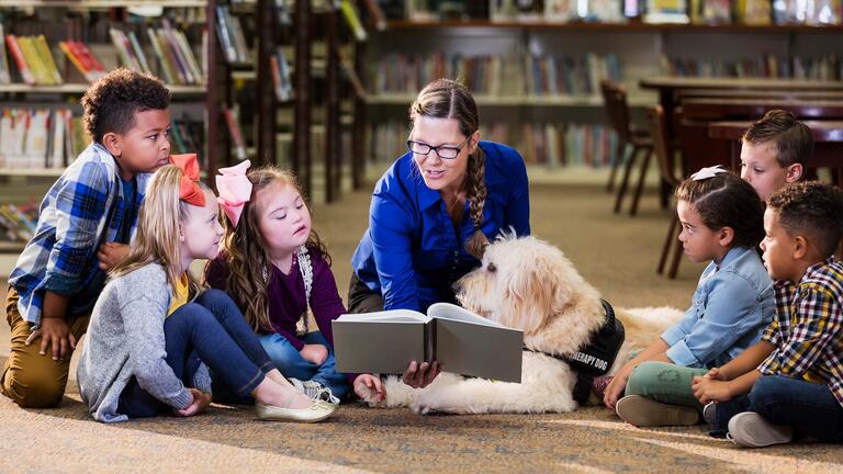 Teacher reads to a group of young children in a library