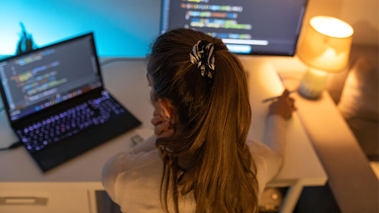 Student looks at computer data at a desk.