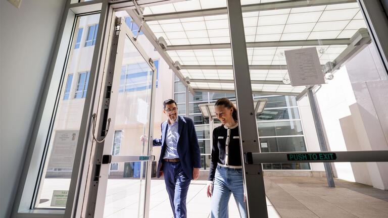 Professor and law student entering USF law building, smiling