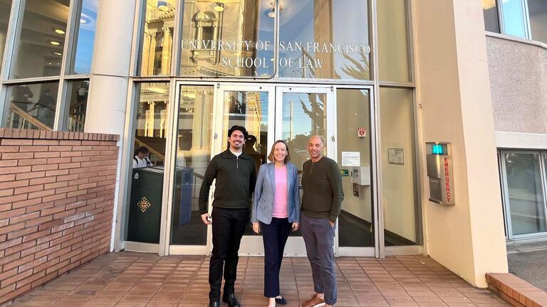 Three people standing in front of the School of Law