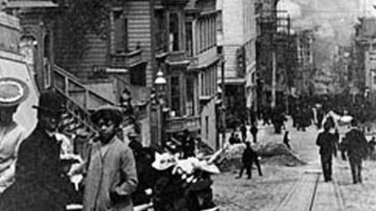 People on steps of house in front of street