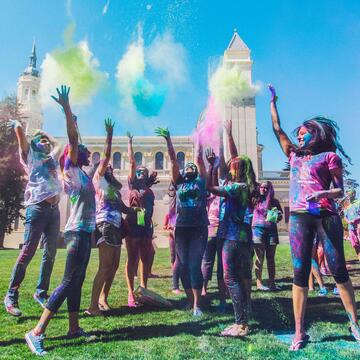 Students jumping up and throwing colorful powder during Holi festival