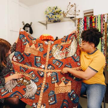 Two people holding a knit blanket