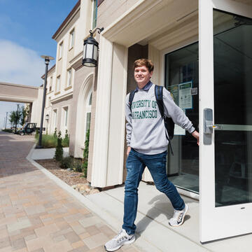 USF student exiting residence hall on Lone Mountain