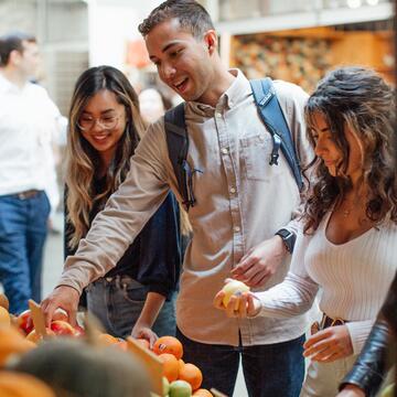 Three students explore a fruit stand at the SF Ferry Building.