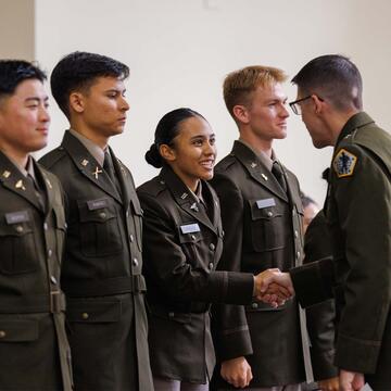 ROTC cadets lined up and shaking an officer's hand