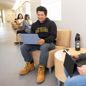student uses laptop in hallway