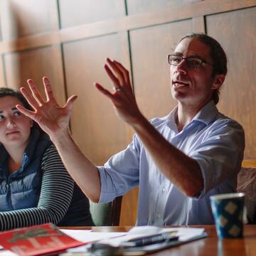 A faculty member gestures with his hands in a seminar class.