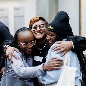 Three USF students hugging