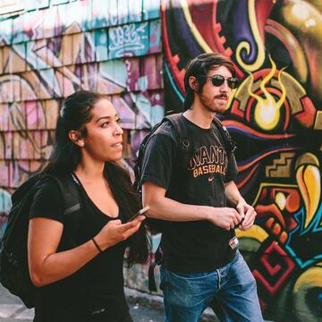 two student walk in front of a mural in SF's mission district