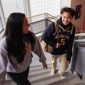 Two students talk while walking up stairs