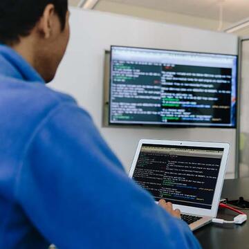 Student looking at code on a laptop and monitor