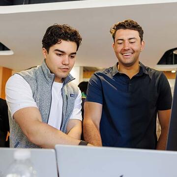 Two students pointing at a laptop